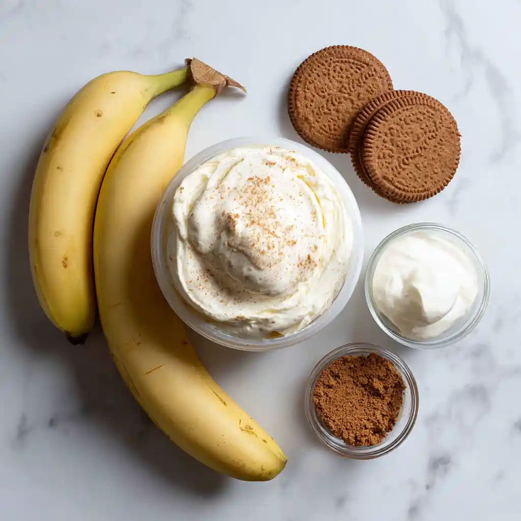 Ingrédients pour cheesecake à la banane : mascarpone, bananes, spéculoos, crème fraîche et vanille sur plan de travail