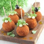Mini croquettes de crabe dorées aux œufs de caille sur planche en bois avec micro-pousses et huile d'olive