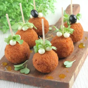 Mini croquettes de crabe dorées aux œufs de caille sur planche en bois avec micro-pousses et huile d'olive