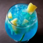 Cocktail bleu sans alcool dans un verre transparent avec glaçons et tranche d'ananas