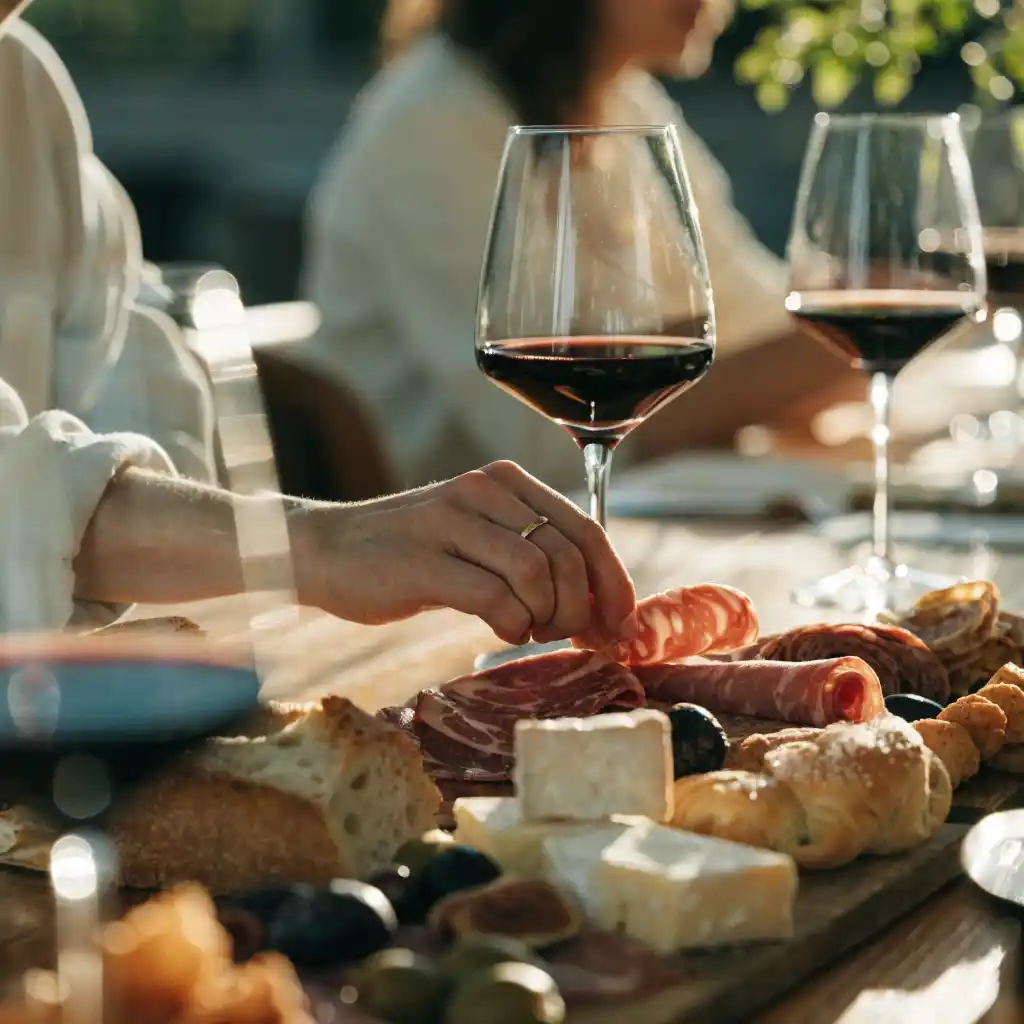 Plateau de charcuterie servi à l'apéritif, convives se servant autour de la table