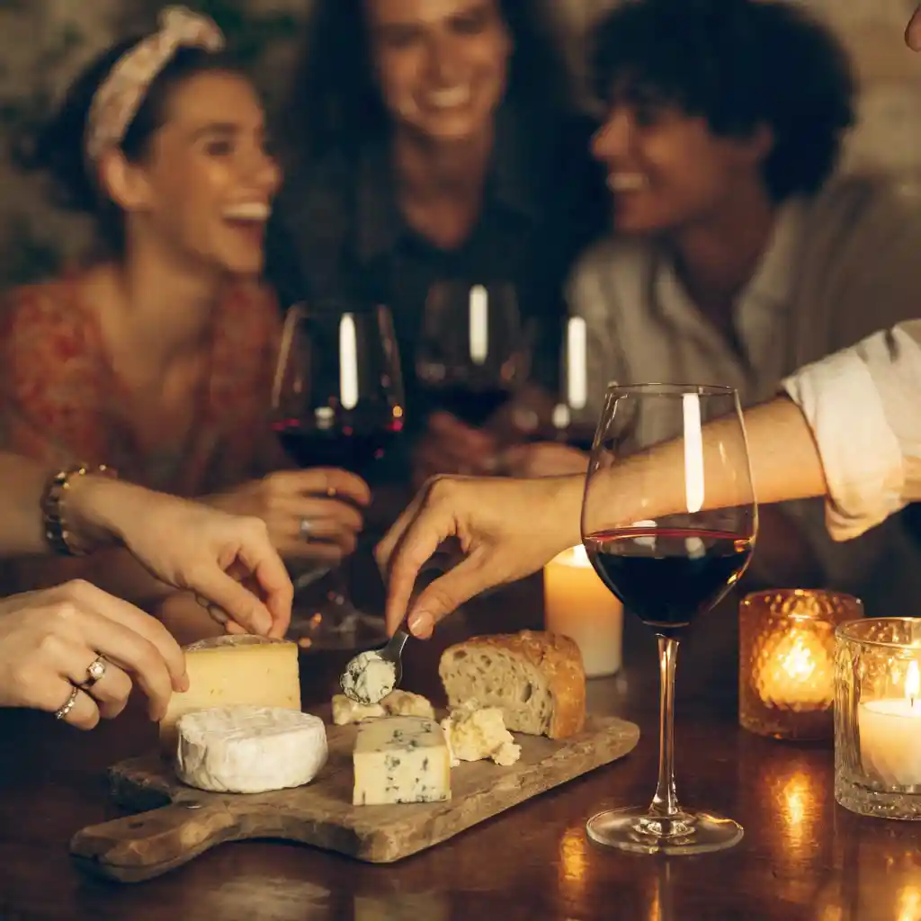 Plateau de fromage servi à l'apéritif, mains d'invités se servant autour de la table