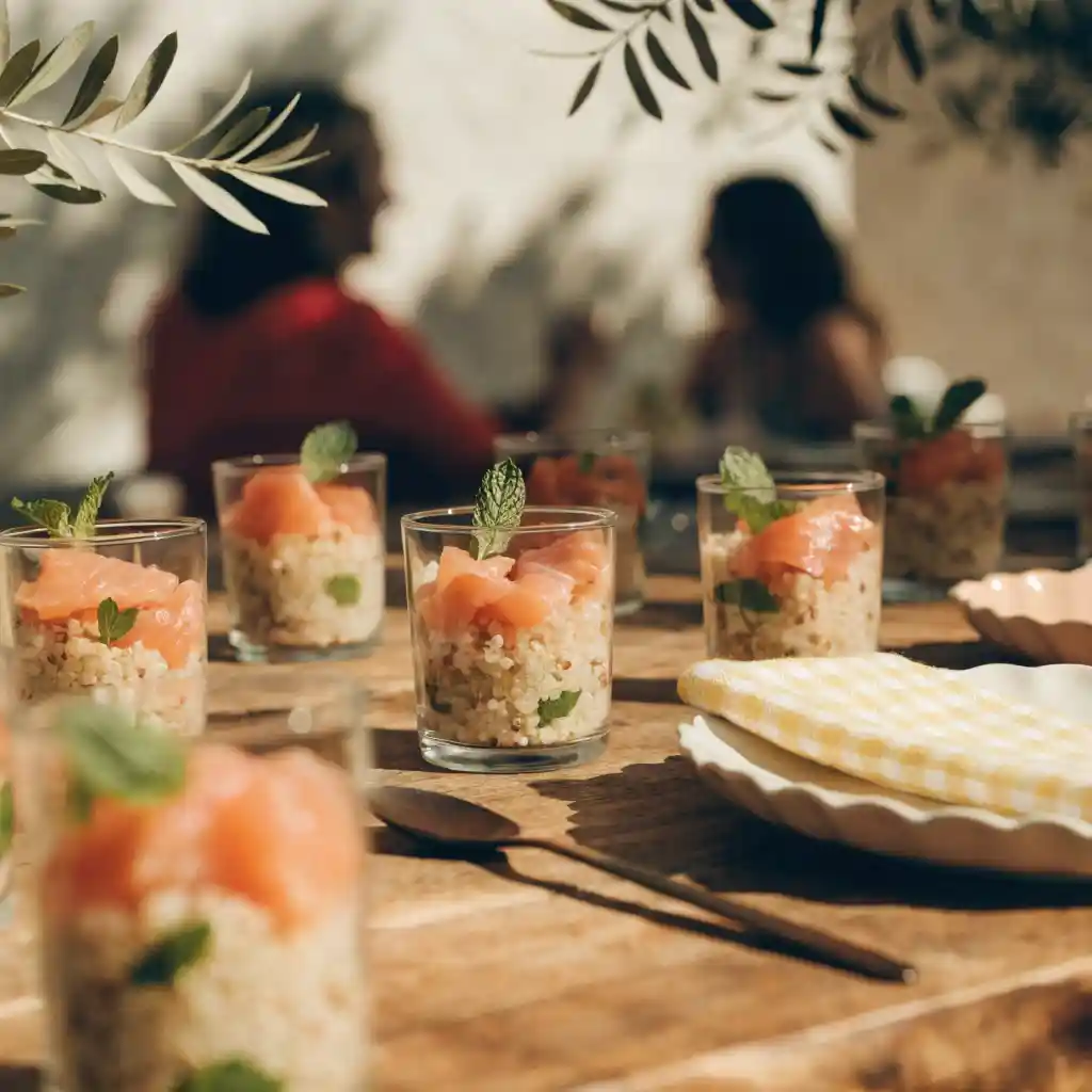 Verrines de salade au quinoa dressées sur une table d'apéritif entre amis