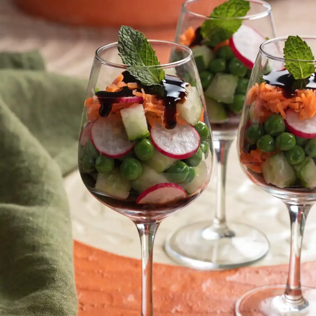 Salade végétarienne printanière servie en verrines avec radis, petits pois, carottes et menthe fraîche