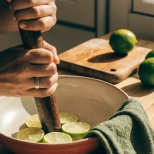 Écraser les rondelles de citron vert au pilon dans le fond du saladier