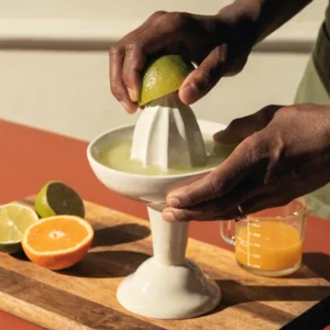 Étape 1 du virgin margarita cocktail : pressage des citrons verts et des oranges au presse-agrumes