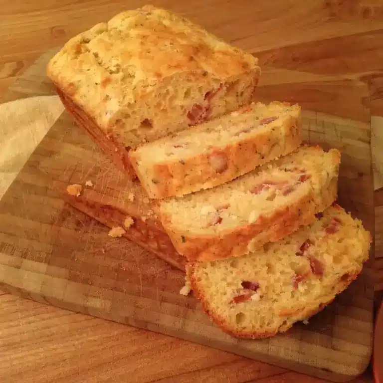 cake au lard et fromage tranché sur une planche en bois, mie aérée parsemée de lardons fumés
