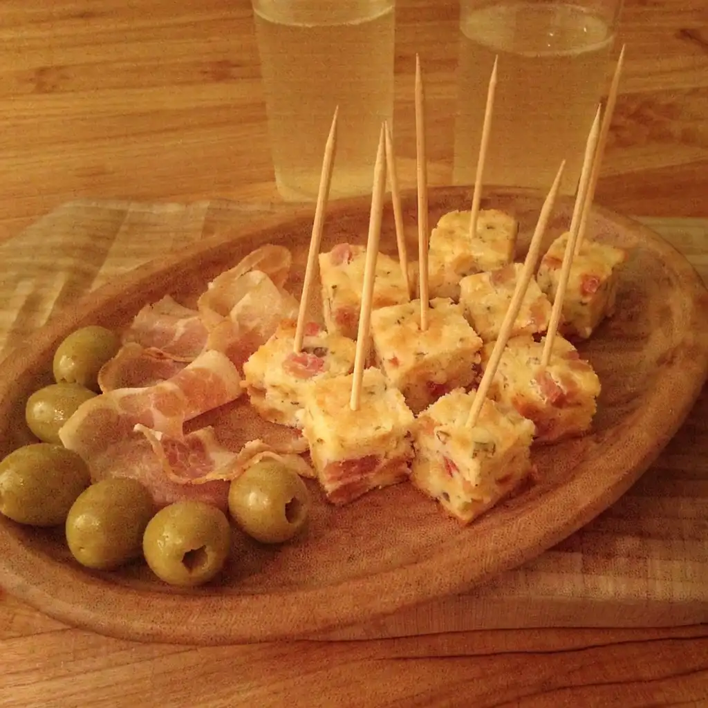 Cubes de cake au lard et fromage piqués sur des piques, servis sur un plateau apéritif