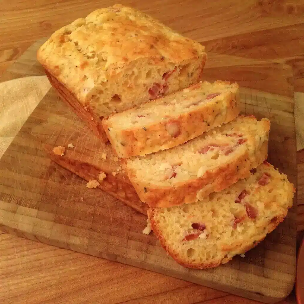 cake au lard et fromage tranché sur une planche en bois, mie aérée parsemée de lardons fumés