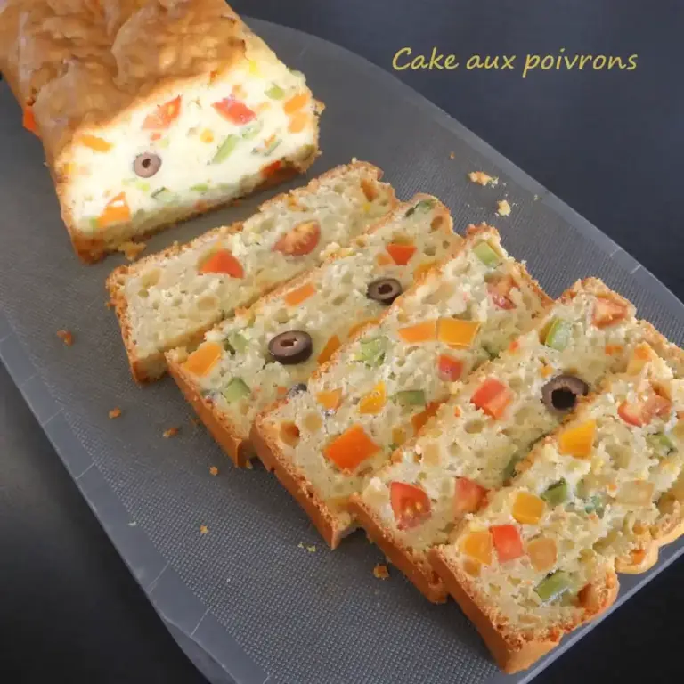 cake aux légumes tranché avec poivrons, tomates et olives noires sur une planche en bois